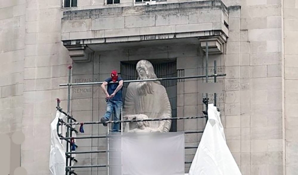 Man scales BBC headquarters wall and hammers at statue.