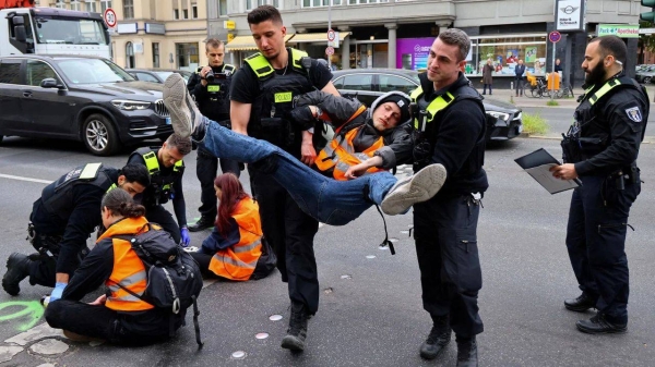 Police officers carry away a climate activist from 'Letzte Generation' (Last Generation), who had glued himself to a street in Berlin