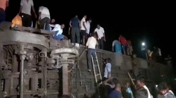 Survivors climb from toppled train carriages following the deadly collision in Balasore, India, on June 2.