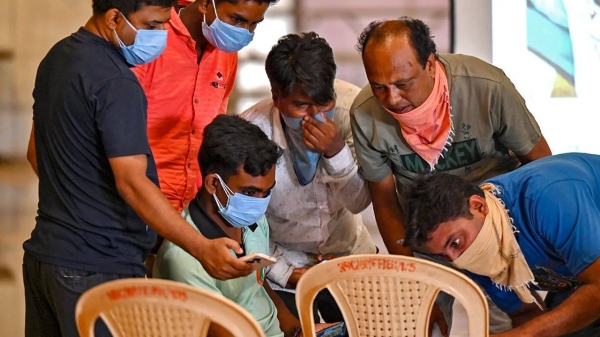 Family members look at photographs on a computer to identify bodies at a temporary mortuary following a train collision near Balasore, in India's eastern state of Odisha, on June 4, 2023