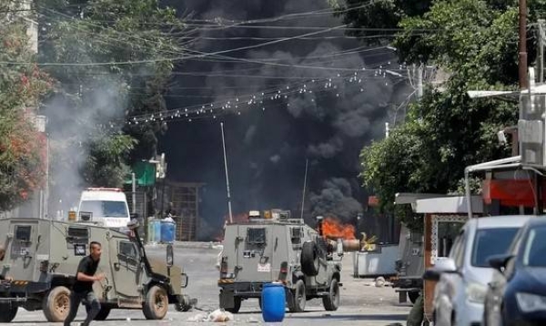 Palestinian armed militants take up positions during a clash with Israeli forces in Jenin on Monday.