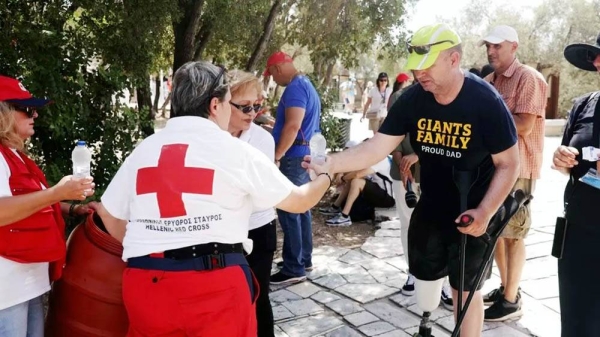 Volunteers from the Hellenic Red Cross handing out water bottles in Athens on Friday. — courtesy Reuters