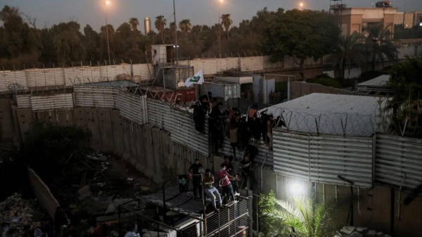 Protesters climb a fence near the Swedish embassy in Baghdad on July 20, 2023.