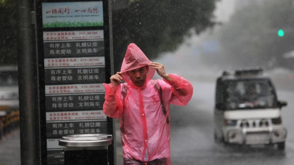 A citizen wearing raincoat walks in a rain on July 30, 2023 in Beijing, China.