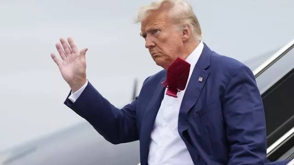 Former President Donald Trump waves as he steps off his plane at Ronald Reagan Washington National Airport in Arlington Thursday.