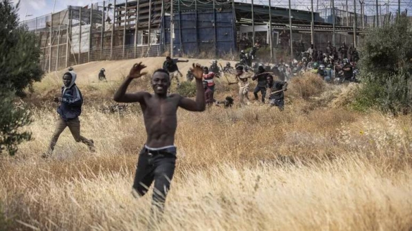 Migrants run on Spanish soil after crossing the fences separating the Spanish enclave of Melilla from Morocco in Melilla.