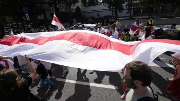 Protesters carrying the white-and-red banner of the Belarusian opposition march past the US Embassy in Warsaw, Poland, on Sunday, Aug. 8, 2021.