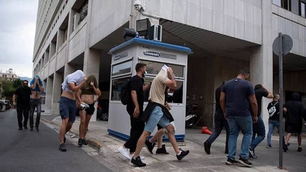 Soccer fans, most of them from Croatia, cover their faces as the police escort them from the General Police Directorate of Attica to court, in Athens, Greece, Sunday, Aug. 13