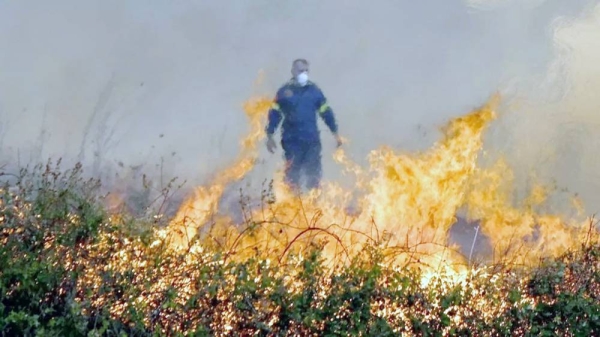 A firefighter stands behind flames during a wildfire in Alexandroupolis, northern Greece. — courtesy EPA-EFE/REX/Shutterstock