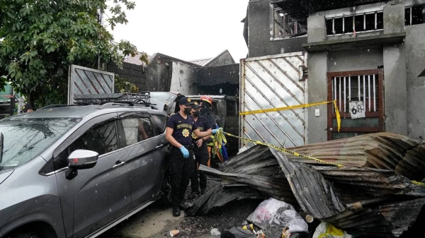 Police outside a house that caught fire in Quezon city, Philippines, on August 31.