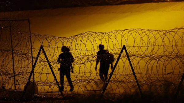 Haitian migrants walk past a razor wire fence deployed to inhibit the crossing of migrants into the United States, as seen from Ciudad Juarez, Mexico July 28, 2023