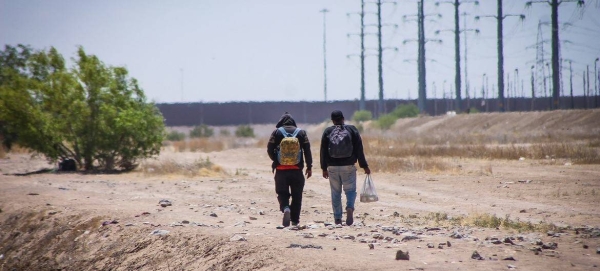 Two men walk near the border between Mexico and the United States. — courtesy IOM/Camilo Cruz