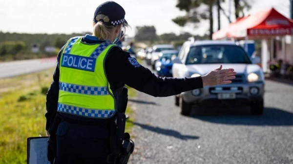 A member of the police force inspects cars at a Border Check Point on Indian Ocean Drive, north of Perth on June 29, 2021