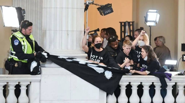 Police try to take down a banner and detain demonstrators as they gather in the rotunda in the Cannon House Office Building