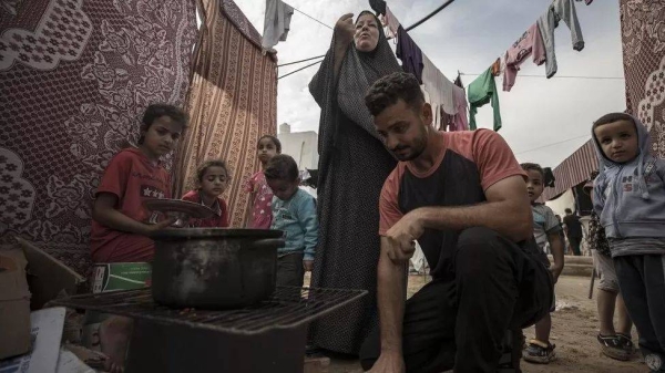 People cook food inside a tent complex in Gaza