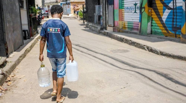 A resident of Rocinha carrying water collected from a natural spring during a heat wave in Rio de Janeiro, Brazil. — courtesy Getty Images