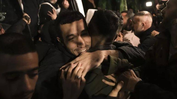 A man smiles as he is welcomed after being released from prison by Israel, in the West Bank town of Ramallah, early Thursday, Nov. 30, 2023