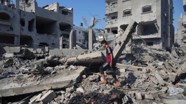Palestinians stand by buildings destroyed in Israeli airstrikes in Deir al-Balah, Saturday, Oct. 14, 2023. Amnesty's report focused on two strikes in this neighborhood