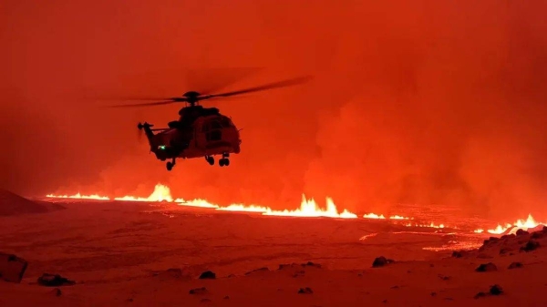 The Icelandic Coast Guard flies a helicopter over the site of the volcanic eruption in Sundhnuk, Iceland on December 19, 2023