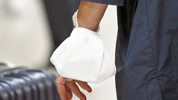 A passenger wears a facemask around their wrist to protect from the recent uptick in COVID cases at Dulles International Airport on Sept. 8, 2023 in Dulles, Va. — courtesy Ricky Carioti/The Washington Post/Getty Images