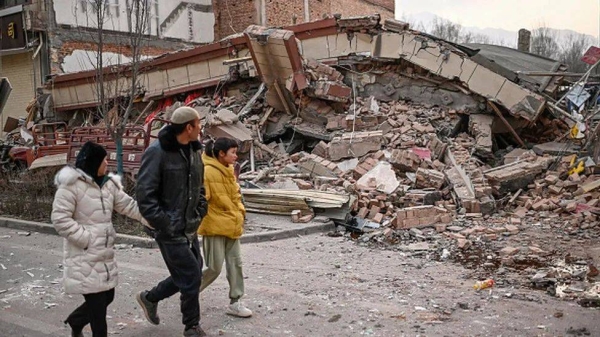 People walk past a collapsed building in Dahejia town in the worst-hit Jishisan county