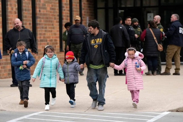 A man and children leave the McCreary Community Building after being reunited following a shooting at Perry High School on Thursday