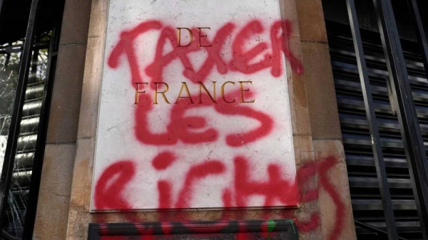 A graffiti reads 'Tax the richs' onto the facade of the national French Bank during a demonstration Thursday, April 13, 2023 in Paris