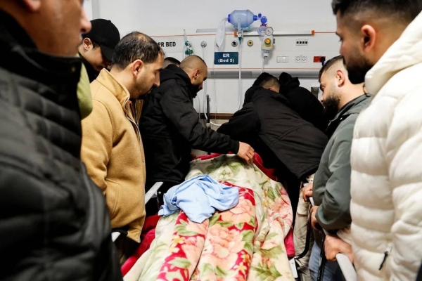 Mourners grieve next to the body of a Palestinian man killed in the raid