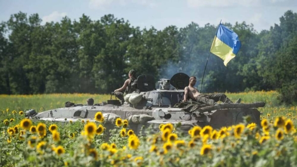 Ukrainian troops ride on an APC with a Ukrainian flag, in a field with sunflowers in Kryva Luka, eastern Ukraine. (File)