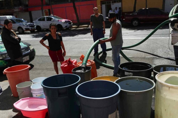 People fill buckets from a water tanker in the Azcapotzalco neighborhood in Mexico City on January 26