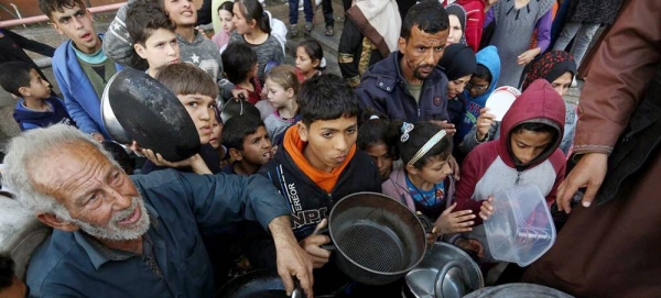 Displaced Palestinians wait to collect food at a distribution point near a school-turned-shelter in Gaza (file). — courtesy UNRWA/Ashraf Amra