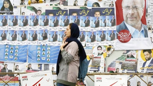 File photo showing a woman walking past electoral posters in Tehran, Iran. — courtesy EPA