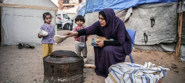 A mother prepares a meal for her children outside their makeshift home in a refugee camp in Khan Younis, Gaza. (file). — courtesy UNICEF/Abed Zagout