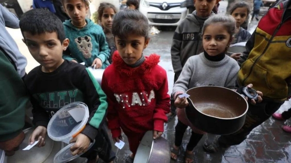 Children with empty pots wait as aid workers distribute food in Gaza City earlier this month