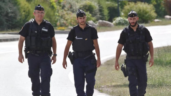 Police officers walk along the road leading to a plant where an attack took place in Saint-Quentin-Fallavier, southeast of Lyon, France, Friday, June 26, 2015