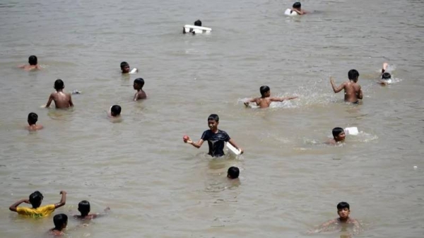 Children cool off in a lake on a hot day in Dhaka