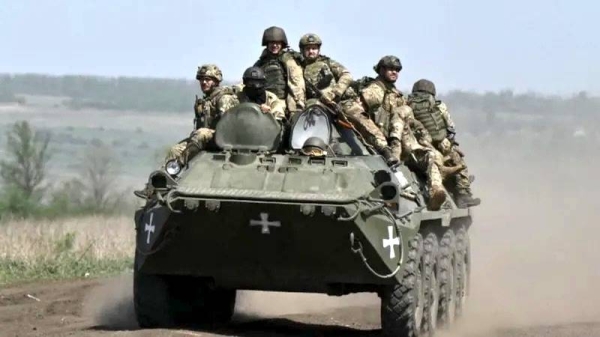 Ukrainian servicemen ride on an armored personnel carrier (APC) in a field near Chasiv Yar. — courtesy Getty Images