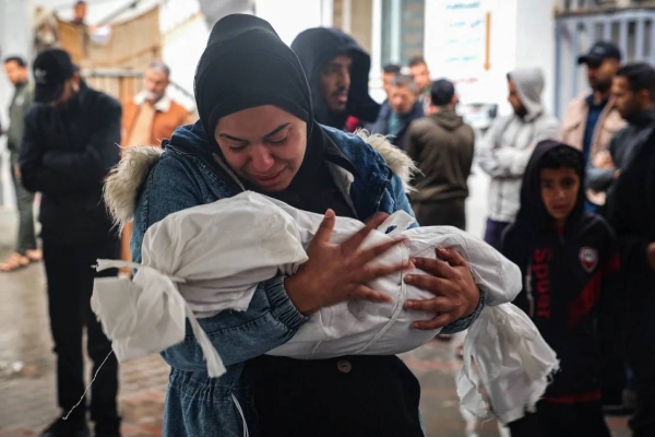 A woman carries the body of a child killed following overnight Israeli strikes on Rafah, May 6, 2024