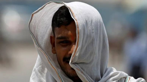 A man covers his face with a cloth to protect himself from the heat