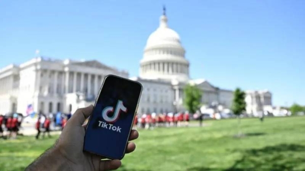 Someone holding a phone with the TikTok logo in front of the US Capitol building,