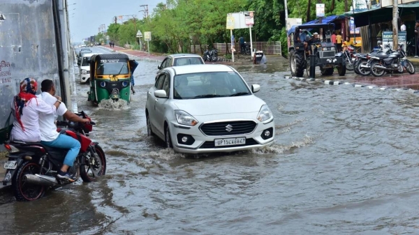 Commuters wade through a waterlogged road during monsoon rainfall at wave city NH9 on June 29, 2024 in Ghaziabad, India