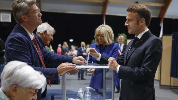 Emmanuel Macron (right), accompanied by his wife Brigitte Macron, holds his ballot to vote in the second round at a polling station in Le Touquet, northern France