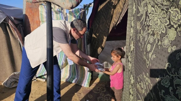 Palestinian-American orthopedic surgeon Jiab Suleiman distributes food to children living in a refugee camp in Khan Younis, in southern Gaza, in April