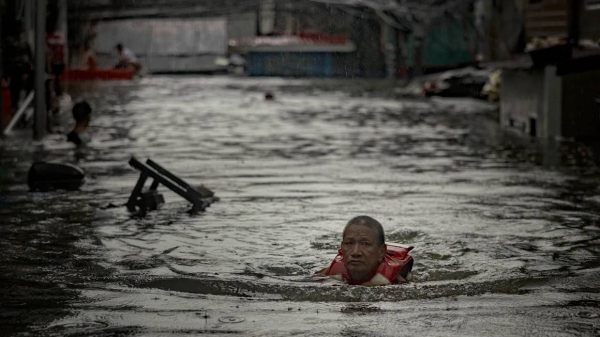 A resident wades floodwaters brought about by Typhoon Gaemi and monsoon rains on July 24, 2024 in Quezon city, Metro Manila, Philippines