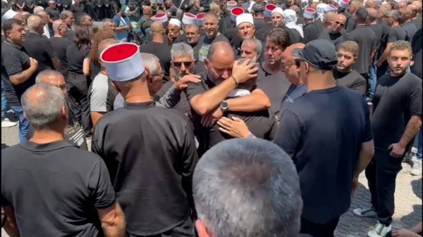 Members of the Druze community in Majdal Shams console each other after the loss of their young