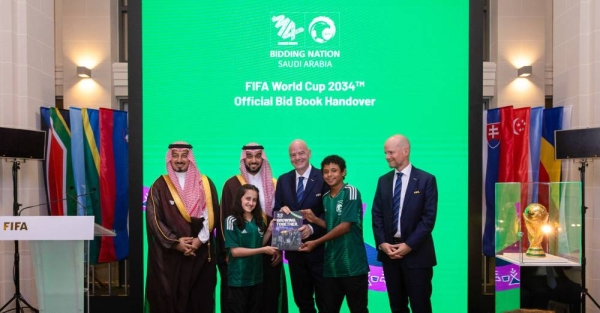 Two young talents hands FIFA's president Saudi Arabia's bid book to host World Cup 2034.