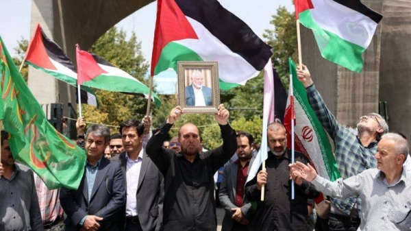 Iranians with Palestinian and Iranian flags carry the portrait of late Hamas leader Ismail Haniyeh in Tehran