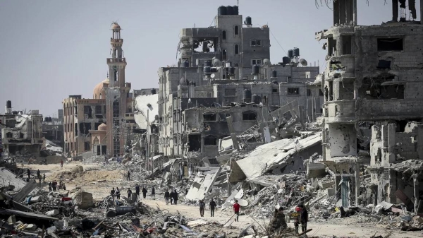 People walk amid the rubble of buildings destroyed during Israeli bombardment in Khan Younis, in southern Gaza, on April 16, 2024