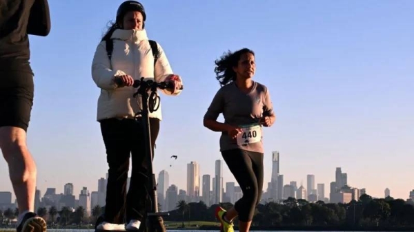 A woman rides on an electric scooter near Albert Park Lake in Melbourne