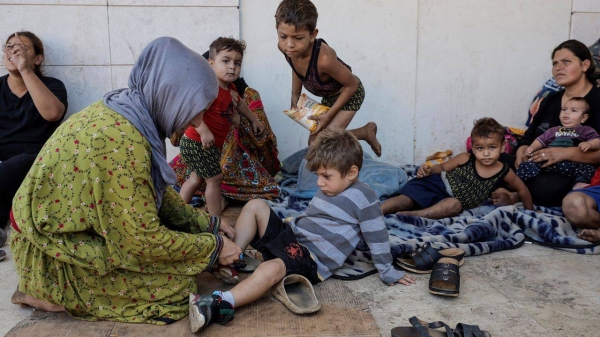 Displaced from Dahiyeh, southern Beirut suburb, Asmaa Kenji, mother of three, helps her son put on his shoes, as they live on the streets of central Beirut after fleeing Israeli air strikes, on September 29.